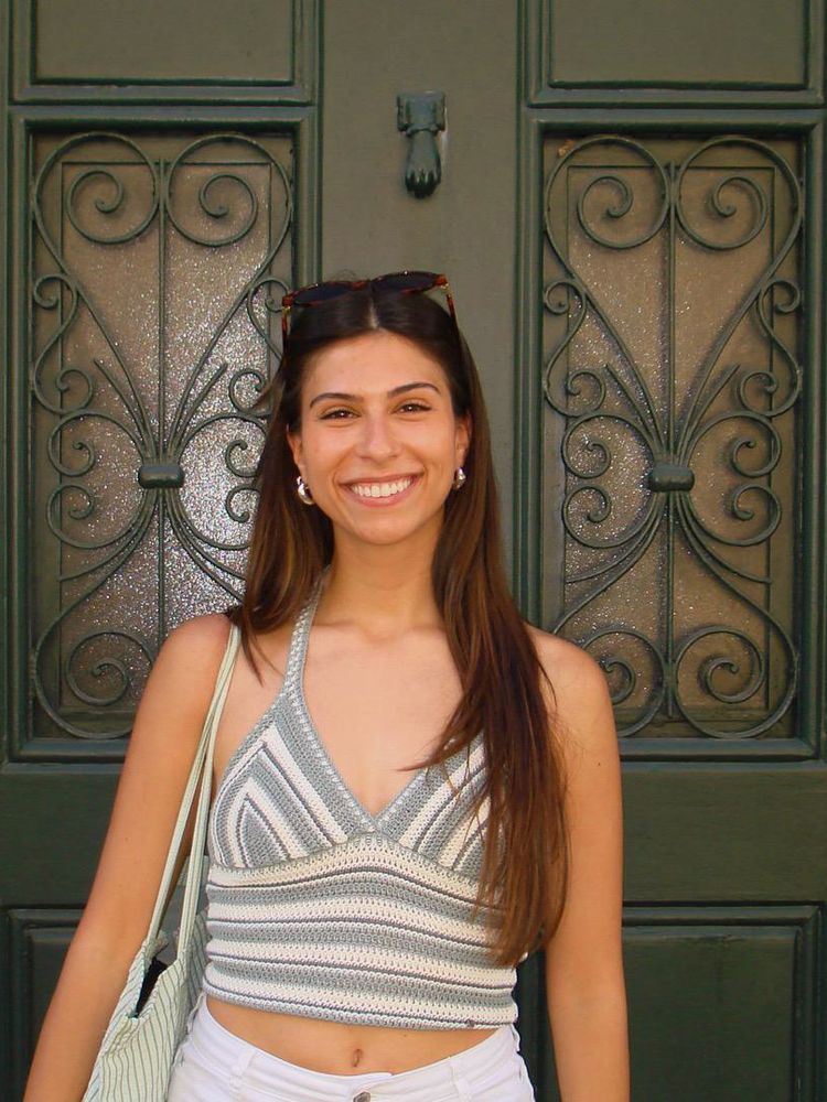 A real photo of a young woman standing outside a dark green door